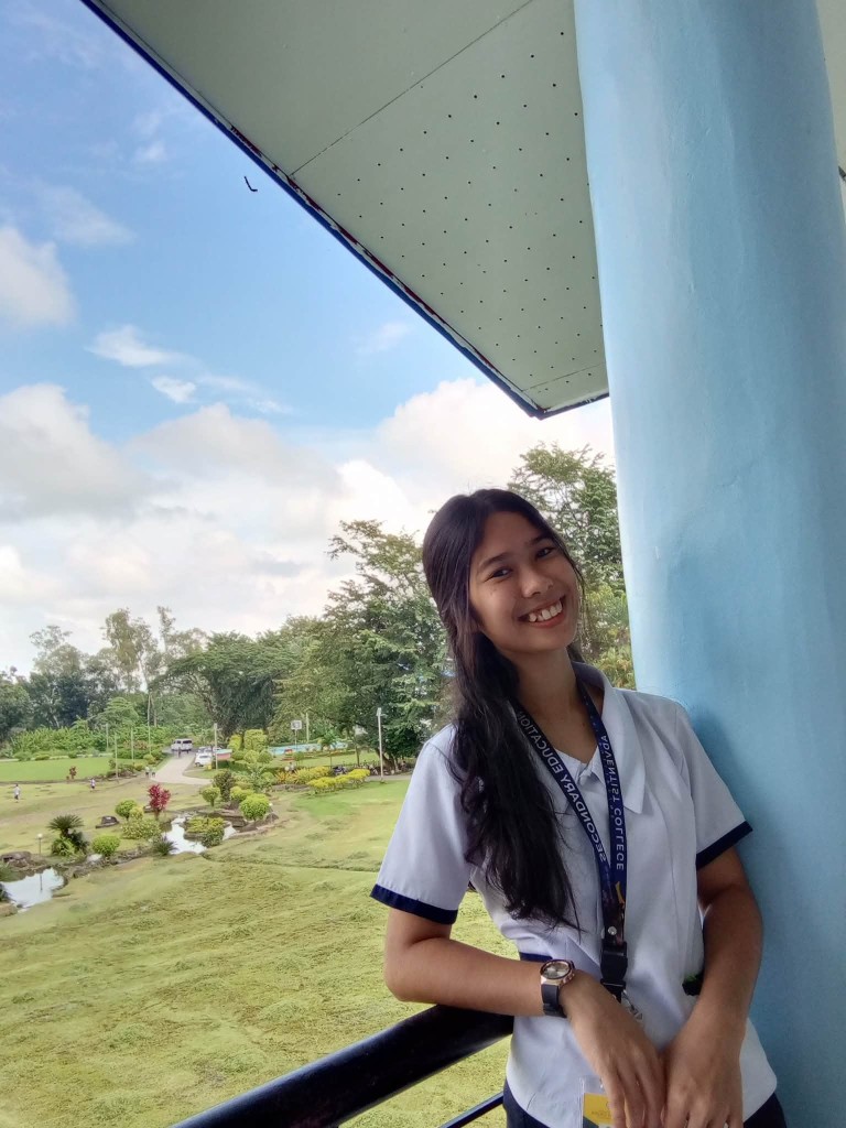 Cristine Manipol Cobre on a campus balcony overlooking the CPAC grounds