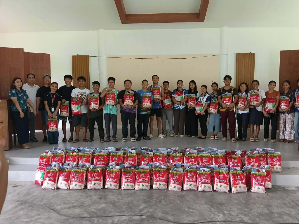 Working students of Central Philippine Adventist College holding 5-kilogram bags of rice from the Zeta Elite School of Nursing Alumni