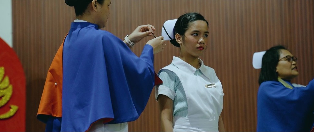 A Nursing student waits as her cap is adjusted during the striping rite