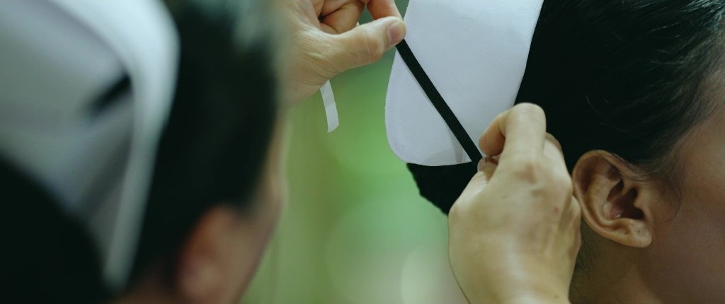Hands fasten the ribbon on a nurse’s cap