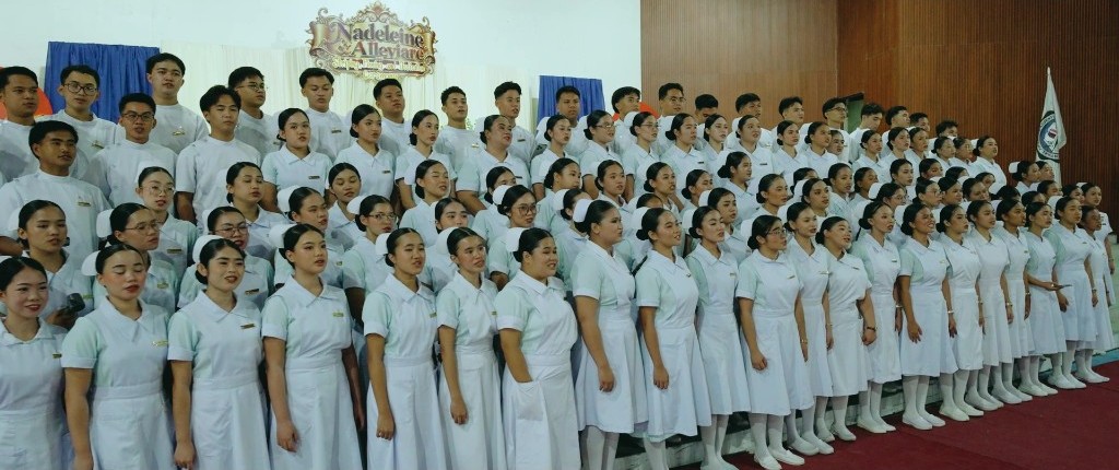 Nadeleine and Alleviare Nursing students in uniform stand on stage during the Striping, Pinning, and Dedication Ceremony