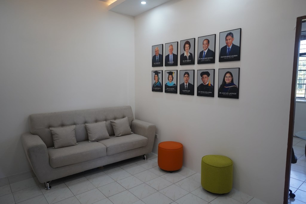 A sitting area with a sofa, colorful ottomans, and framed portraits of CPAC leaders and administrators